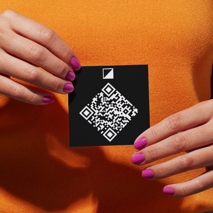 Person holding a black card with a QR code against an orange background